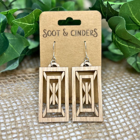 Rectangular art deco earrings made of red oak and recycled sterling silver on a 'Soot & Cinders' branded card with green leaves in the background


