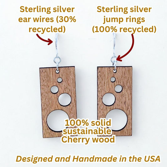 Rectangular solid cherry wood earrings with circle cutouts and recycled sterling silver on a white background to make an infographic, highlighting recycled materials and sustainability.