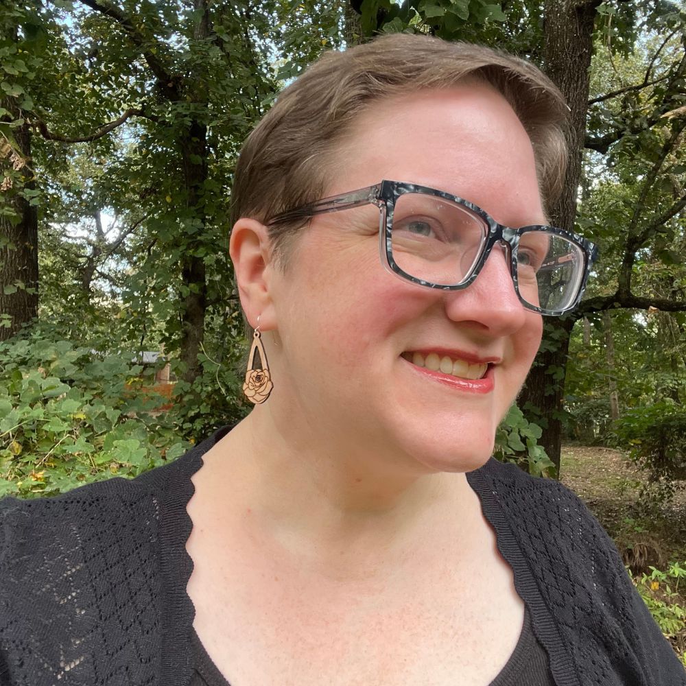 woman wearing black cardigan and mahogany teardrop earrings with a rose engraved on them 