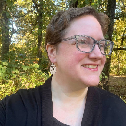 Woman with glasses and a black top standing in a forest wearing Octagonal red oak and recycled sterling silver earrings 