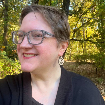 Woman with glasses and a black top standing in a forest wearing Octagonal red oak and recycled sterling silver earrings 