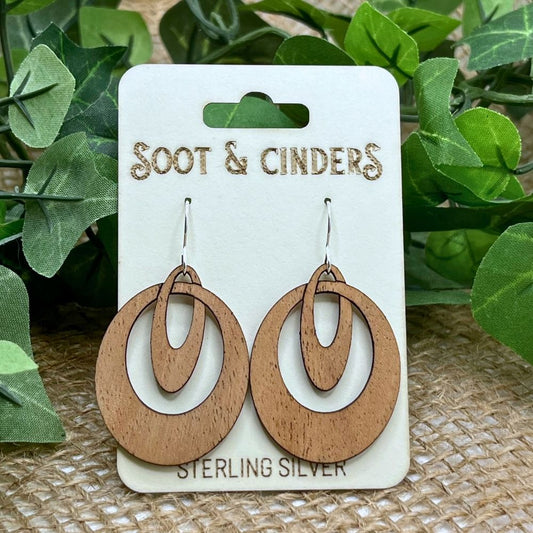 Cherry wood and recycled sterling silver earrings on a 'Soot & Cinders' branded card with green leaves in the background