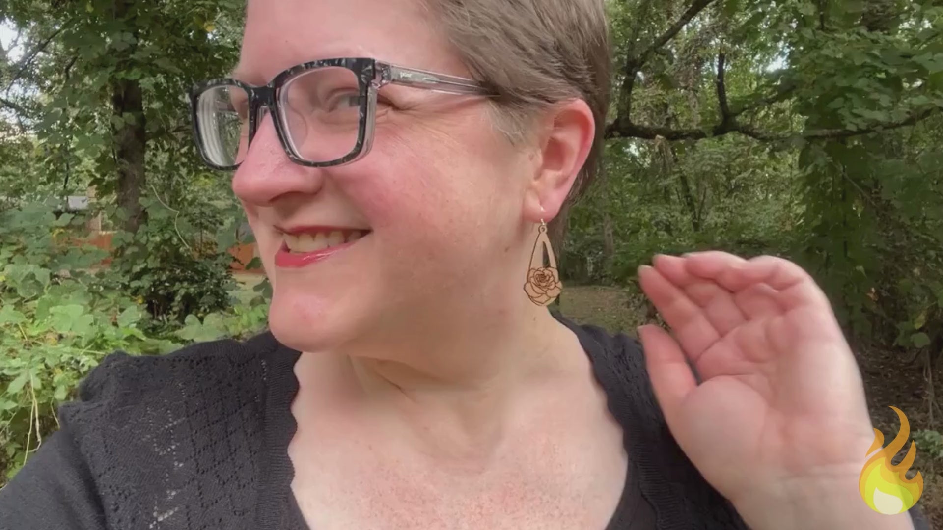 video showing a woman wearing wooden earrings engraved with roses, then a hand is shown holding the earrings while the earrings' sustainability traits are listed.