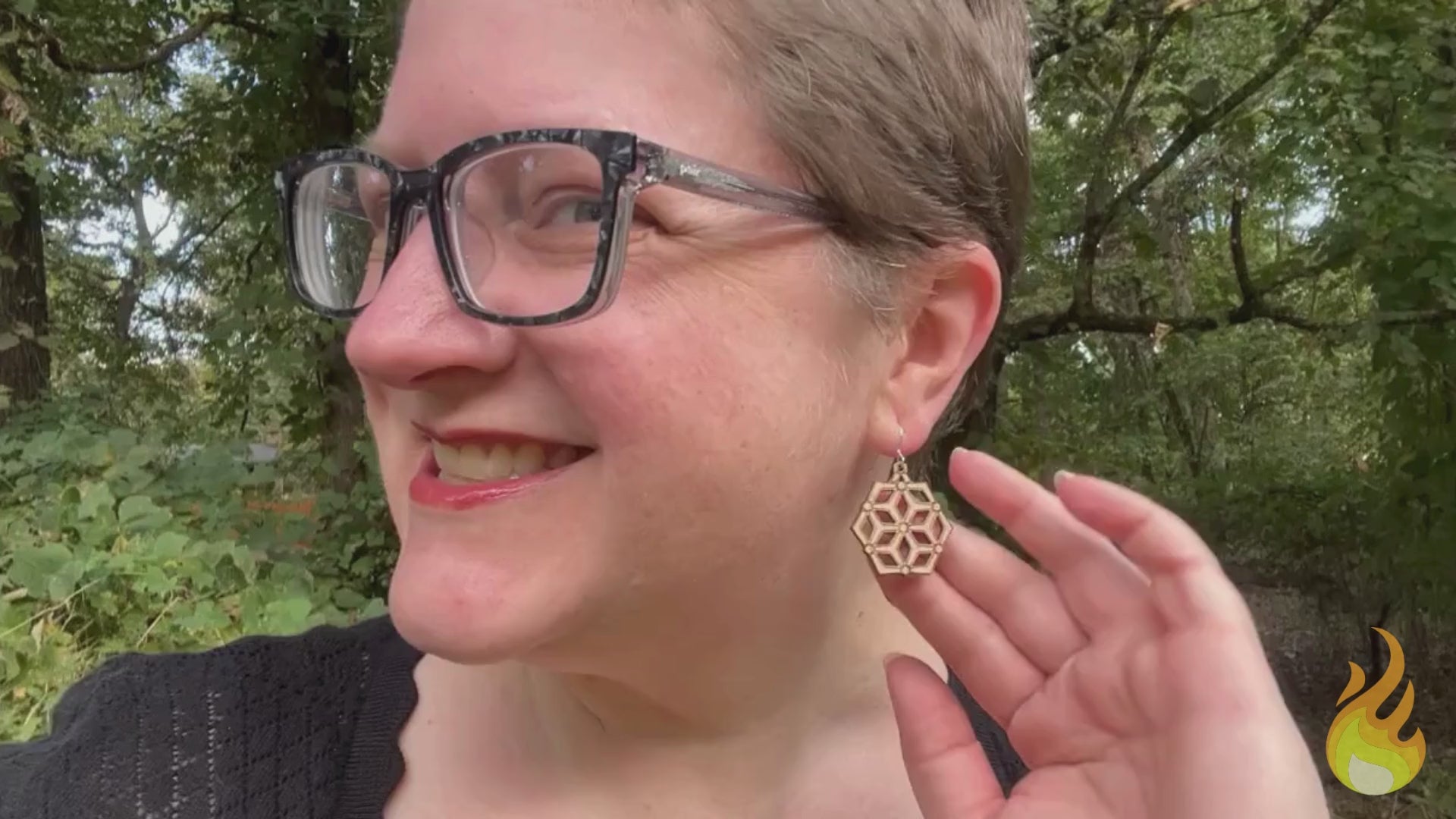 video showing a woman modeling hexagonal wood and silver earrings, then a hand is shown holding the earrings while the earrings' sustainability traits are listed