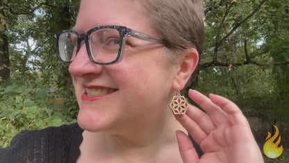 video showing a woman modeling hexagonal wood and silver earrings, then a hand is shown holding the earrings while the earrings' sustainability traits are listed