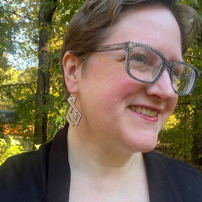 Woman wearing glasses and earrings with a blurred natural background