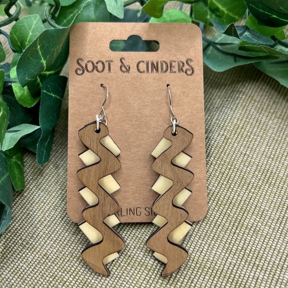zigazag two tone Wooden earrings on a 'Soot & Cinders' branded card with green leaves in the background